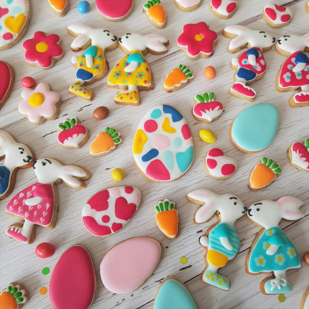 Vibrant Easter-themed cookies with bunnies and eggs on a wooden surface.